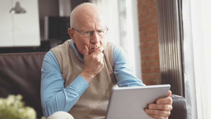 confused man holding a tablet Photo Piotr Adamowicz Dreamstime. For article: Advice from Amy - older man baffled by dating