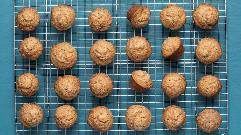 A cooling tray of Sweet Applesauce Mini Muffins from America's Test Kitchen. Everyone will love the convenience of this little snack.