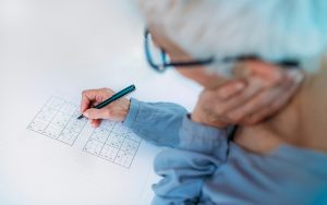 Man doing puzzle, possibly Sudoku Image