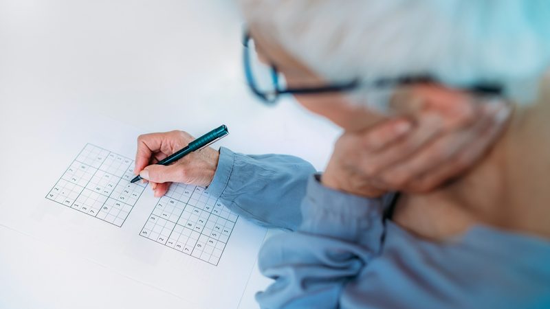 Man doing puzzle, possibly Sudoku Image