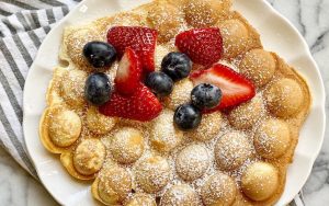 bubble waffles for snacking fun, topped with strawberries and blueberries. This recipe is worth getting a fun, new waffle maker. Image