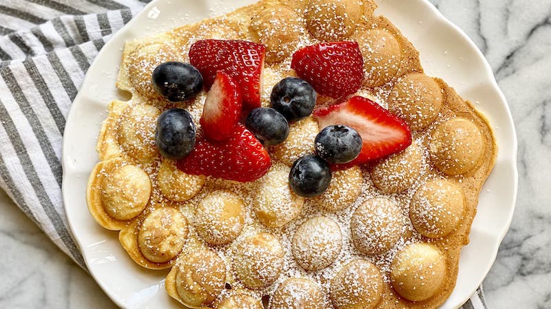 bubble waffles for snacking fun, topped with strawberries and blueberries. This recipe is worth getting a fun, new waffle maker. Image