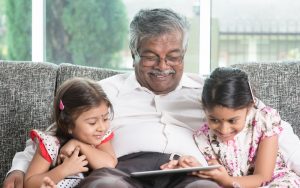granddad and granddaughters looking at a tablet possibly playing a puzzle Szefei Dreamstime Image