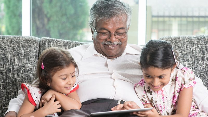 granddad and granddaughters looking at a tablet possibly playing a puzzle Szefei Dreamstime Image