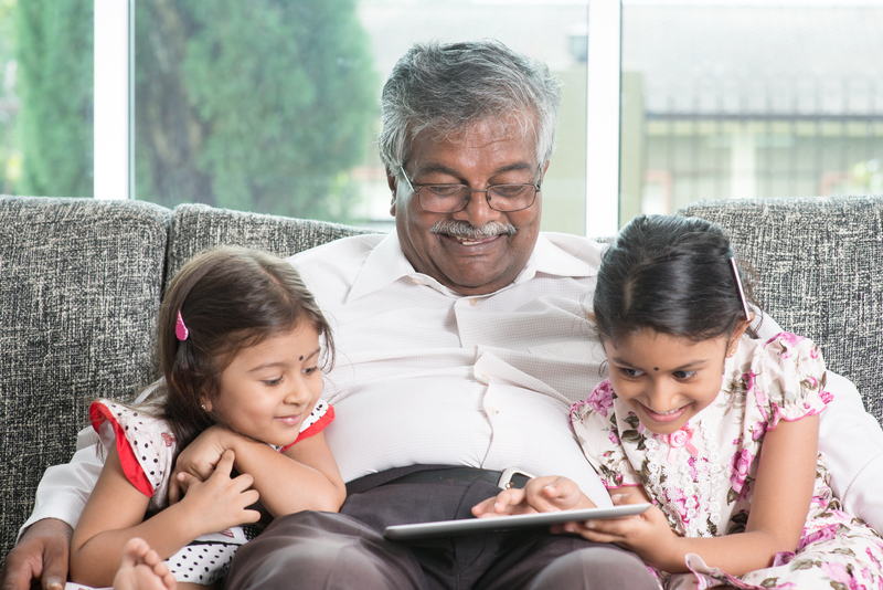 granddad and granddaughters looking at a tablet possibly playing a puzzle Szefei Dreamstime