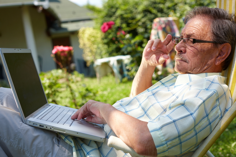 man outside on a laptop, possibly working on a puzzle. Photo by Nyul Dreamstime