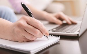Woman with laptop computer doing puzzle or taking notes on the side. Photo by Milkos, Dreamstime Image