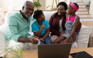 grandparents and grandkids laughing, gathered around a laptop, possibly working a puzzle like Jumble together. Wavebreakmedia Ltd Dreamstime Image