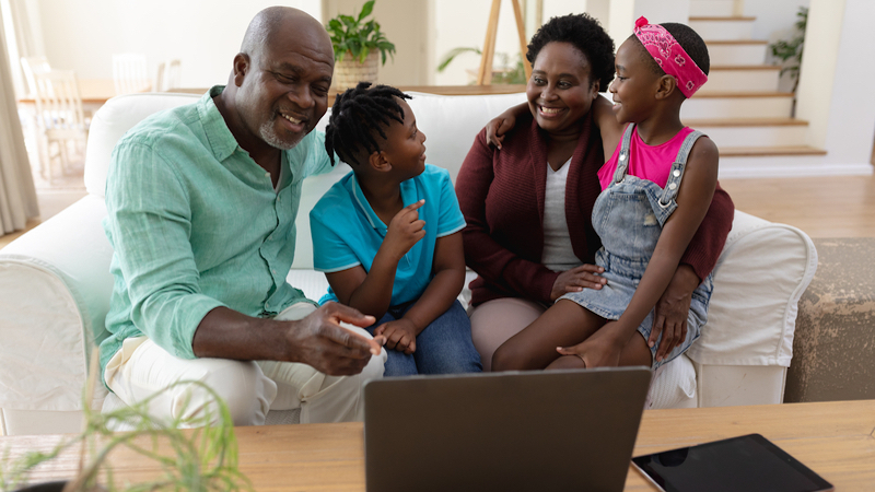 grandparents and grandkids laughing, gathered around a laptop, possibly working a puzzle like Jumble together. Wavebreakmedia Ltd Dreamstime