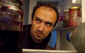 man looking in refrigerator at night Photo by Rigmanyi Dreamstime. For article, A dietitian looks at whether nighttime eating can make a person gain weight and at other factors that may be at play. Image