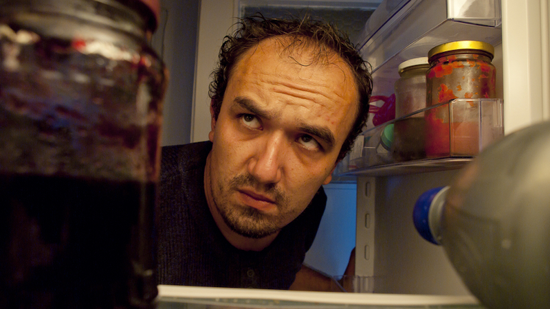 man looking in refrigerator at night Photo by Rigmanyi Dreamstime. For article, A dietitian looks at whether nighttime eating can make a person gain weight and at other factors that may be at play.