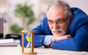 office worker looking at hourglass photo by Elnur Dreamstime. For article, Humorist Greg Schwem extolls the virtues (and hints at hidden downsides) of an idea whose time has come: the one-day work week. Image
