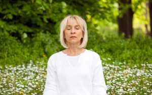 mindfulness and positivity: woman meditating outside Photo by Milovan Radmanovac Dreamstime.com Image
