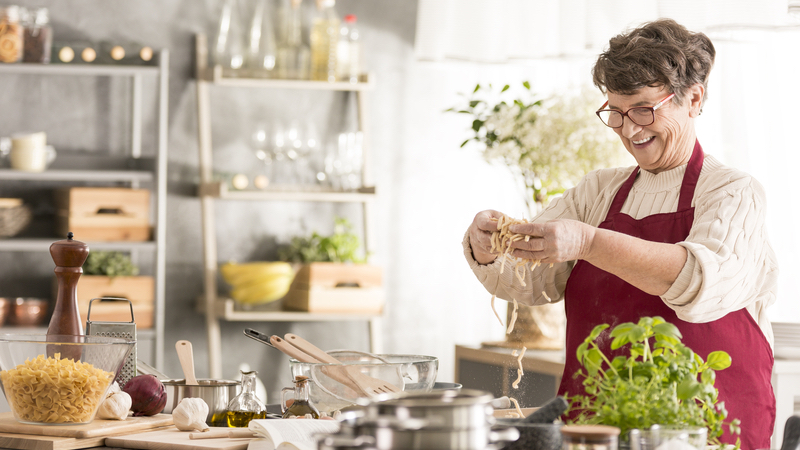 happy woman cooking pasta and vegetables in her kitchen. Photo by Katarzyna Bialasiewicz Dreamstime. For article on responses to uppity vegetarians and vegans