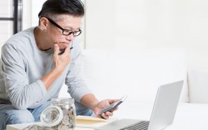 man concerned about his finances looking at laptop and calculator Photo by Szefei Dreamstime. For article, Your retirement savings will affect the comfort of your post-retirement life. If you’re starting late, here are tips to boost your savings. Image
