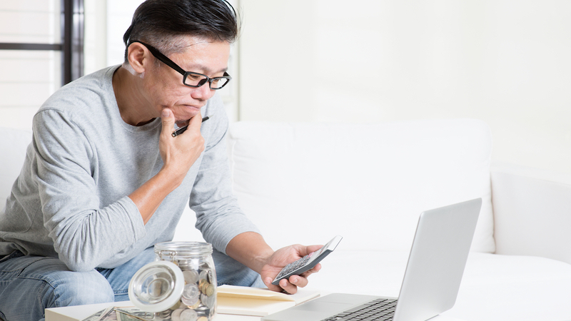 man concerned about his finances looking at laptop and calculator Photo by Szefei Dreamstime. For article, Your retirement savings will affect the comfort of your post-retirement life. If you’re starting late, here are tips to boost your savings.