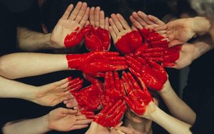 Photo of about 14 palms of hands painted with a red heart. For article, Ask Amy: our son is in a polyamorous relationship Image