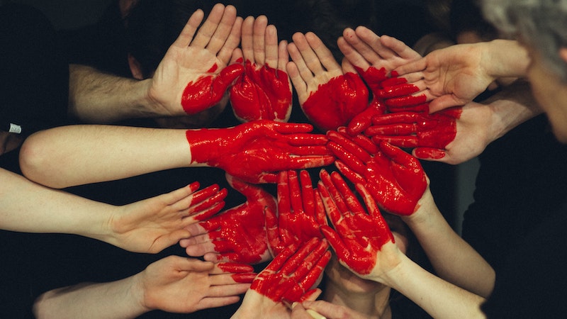 Photo of about 14 palms of hands painted with a red heart. For article, Ask Amy: our son is in a polyamorous relationship