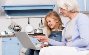 grandmom and granddaughter on laptop, maybe doing puzzles. Photo by Katarzyna Bialasiewicz Dreamstime Image