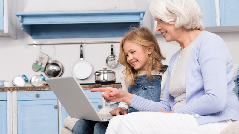 grandmom and granddaughter on laptop, maybe doing puzzles. Photo by Katarzyna Bialasiewicz Dreamstime Image