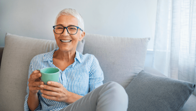happy senior woman on sofa, drinking tea to preserve health