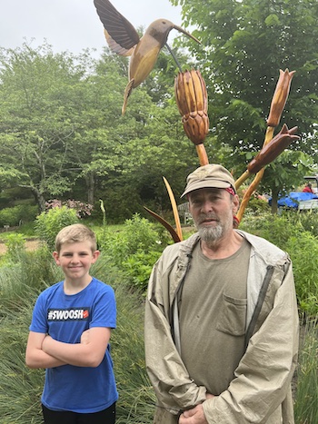 David Rogers, Big Bugs artist, standing in front of his hummingbird art at Lewis Ginter Botanical Garden.