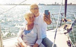 A retired couple taking a selfie, lounging on a sailboat, for article on why to start sailing in retirement Image