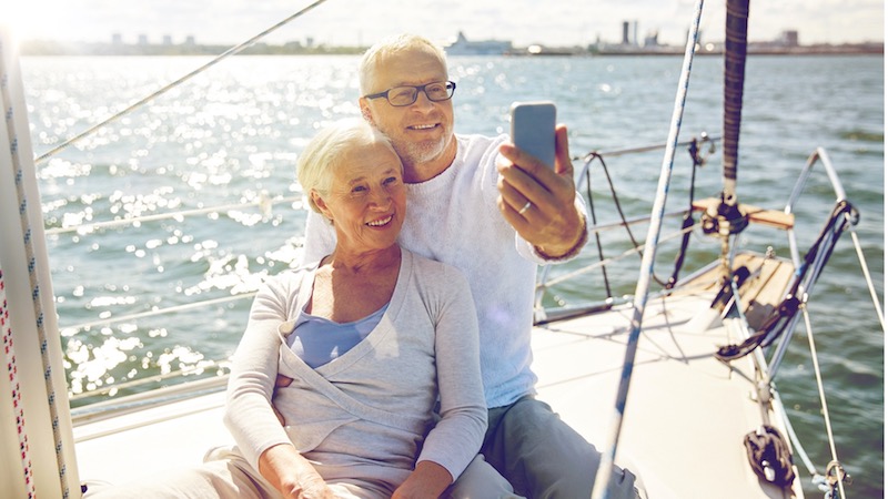 A retired couple taking a selfie, lounging on a sailboat, for article on why to start sailing in retirement Image