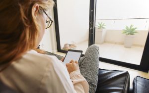 Looking over a woman's shoulder as she readers her tablet. Her husband snoops on her when she’s on her computer or smartphone, despite her requests for him not to. “Invaded” reader asks advice columnist Amy Dickinson to weigh in, in this edition of “Ask Amy.” Image