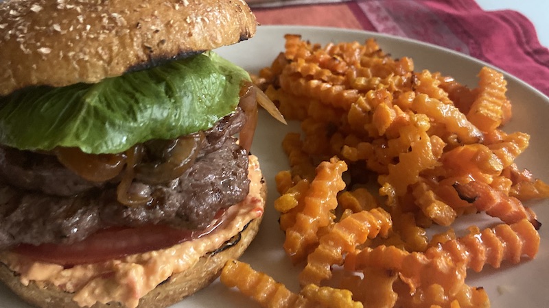 These venison burgers on the grill – with a spicy cheese sauce and browned onions and mushrooms – help spice up the summer.  Image