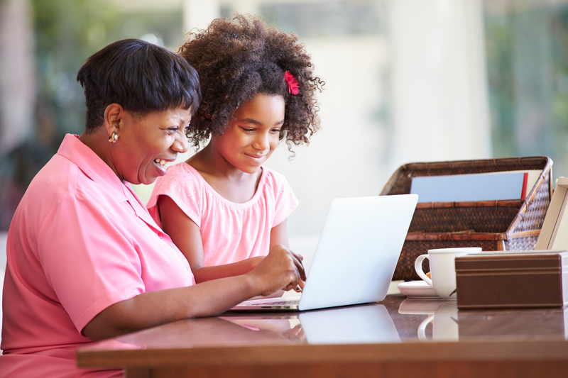 grandmother and granddaughter laptop maybe working on a puzzle - photo by monkey business images, dreamstime