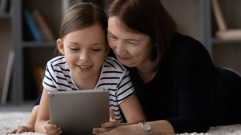 grandmother and granddaughter looking at a tablet, possibly doing puzzles. Photo by Fizkes Dreamstime