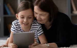 grandmother and granddaughter looking together at a tablet, maybe playing a puzzle - photo by Fizkes Dreamstime Image