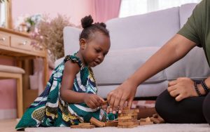 Black child and adult playing puzzle game for Jumble puzzles. Photo by Chayantorn Tongmorn, Dreamstime Image