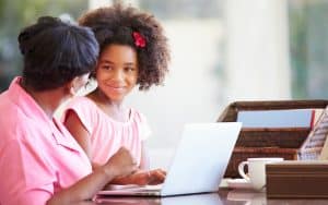 grandmother and granddaughter at a laptop, maybe working on a puzzle like Boggle or Jumble. Photo by Monkey Business Images, Dreamstime Image