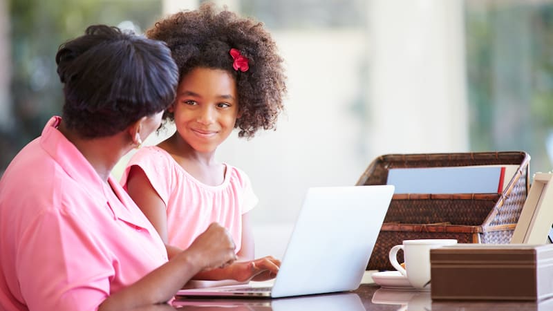 grandmother and granddaughter at a laptop, maybe working on a puzzle like Boggle or Jumble. Photo by Monkey Business Images, Dreamstime