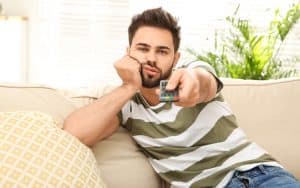 lazy man watching TV - photo by Chernetskaya, Dreamstime. A woman is mad at her deadbeat son-in-law, who lets his wife do all the work, from childcare to a fulltime job. See what Ask Amy advises. Image