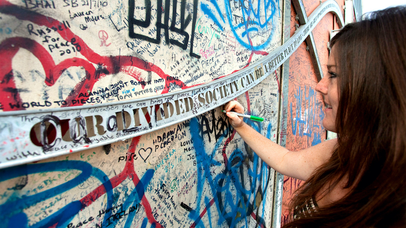 Writing on Belfast's Peace Wall. In Rick Steves’ Europe, the travel writer examines the context of several significant European walls: built in times of mistrust and danger, torn down to be displaced by interdependence and empathy. In Rick Steves’ Europe, the travel writer examines the context of several significant European walls: built in times of mistrust and danger, torn down to be displaced by interdependence and empathy. Image by Dominic Arizona Bonuccelli.