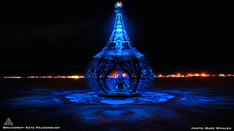 Image from Braindrop and Kate Raudenbush at Burning Man 2009-photo by Marc Whalen. Braindrop is a meditation space built to honor the element of water. This Portrait shows the artist Kate raudenbush meditating inside at Burning Man 2009. the line form designwork is inspired by the seed of life geomentry and Japanese woodcuts. the 17’ tall water drop contains a 7’ diameter hexagonal white bed inside and a glass bead chandeleir pouring down from above. origianlly commissioned by Phill Blaine curator for the All Points West Festival in Liberty Park NJ in 2009. later installed at Burning Man for the Evoloution theme in 2009. it is one of my most installed artworks, and each time i installed it - it rained, sometimes a hurricaine and severe thunderstorms. The only time it didn’t storm was when it was finally purchased by Arthur Meyerovich in 2013. More of What's Booming RVA: Sept. 29 and Beyond. Plus announcements and down-the-road events