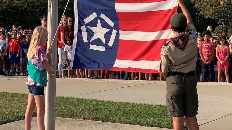 Schoolchildren raise the Freedom Flag at their school. In the wake of 9/11, a restaurateur in Richmond, Virginia, created the Freedom Flag to symbolize the import of the day and to honor the importance of freedom into the future.