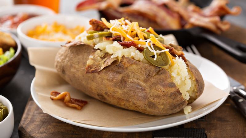 Baked potato with toppings. Image by Elena Veselova, Dreamstime. A baked potato bar with creative toppings like these are perfect for football watch parties, game night, or simply an easy dinner at home.