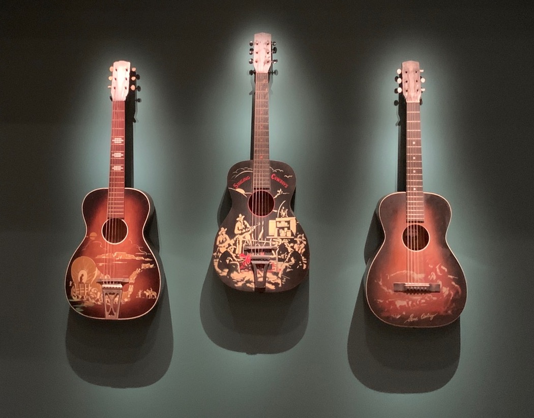 three cowboy guitars on display at the VMFA exhibition, "Storied Strings."