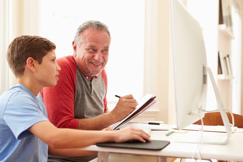 Granddad and grandson working on a computer, perhaps for a Jumble Puzzles