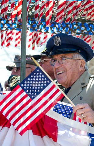 older veteran in a crowd surrounded by small American flags. Photo by Susan Sheldon.