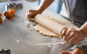 woman using a rolling pin to roll out dough. Image by Lido. Her husband asked her to prepare additional baked goods for a gluten-free guest, but she’s feeling a bit overwhelmed. See what “Ask Amy” says. Image