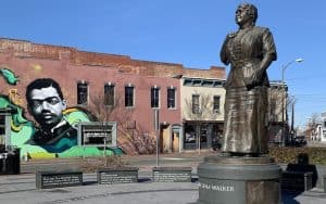 Maggie Walker statue with mural. By Annie Tobey. This week in Richmond, blend contemporary music and humor with insights from Black History Month, in “What’s Booming RVA: Life in America.” Image