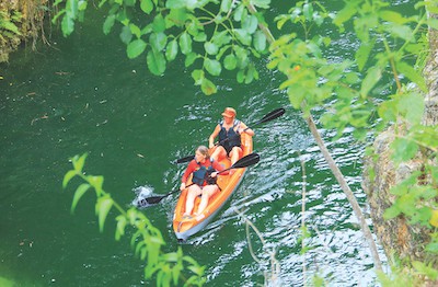shot from above: a woman and men in a sit-upon kayak