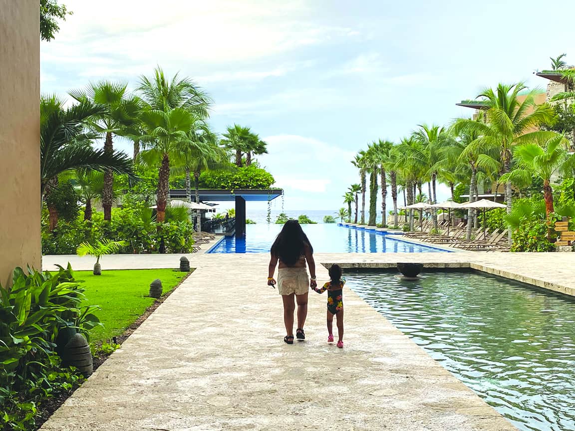 Adult and child walking beside the pooled waters at Hotel XCaret Mexico