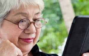 Woman looking at a tablet, perhaps doing a puzzle, like the Boggle or Jumble Image