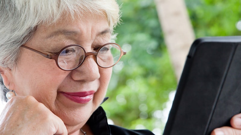 Woman looking at a tablet, perhaps doing a puzzle, like the Boggle or Jumble